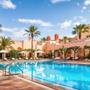 Luxurious sparkling pool, elegant Moroccan hotel architecture, serene adult oasis.