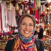 Woman in Moroccan market with colorful textiles and lamps