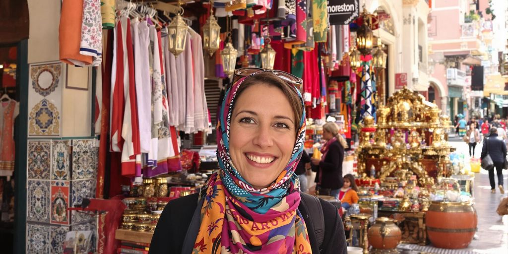Woman in Moroccan market with colorful textiles and lamps